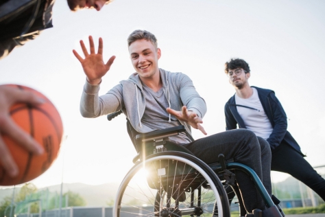 Jugendlicher im Rollstuhl spielt mit anderen Jugendlichen Basketball